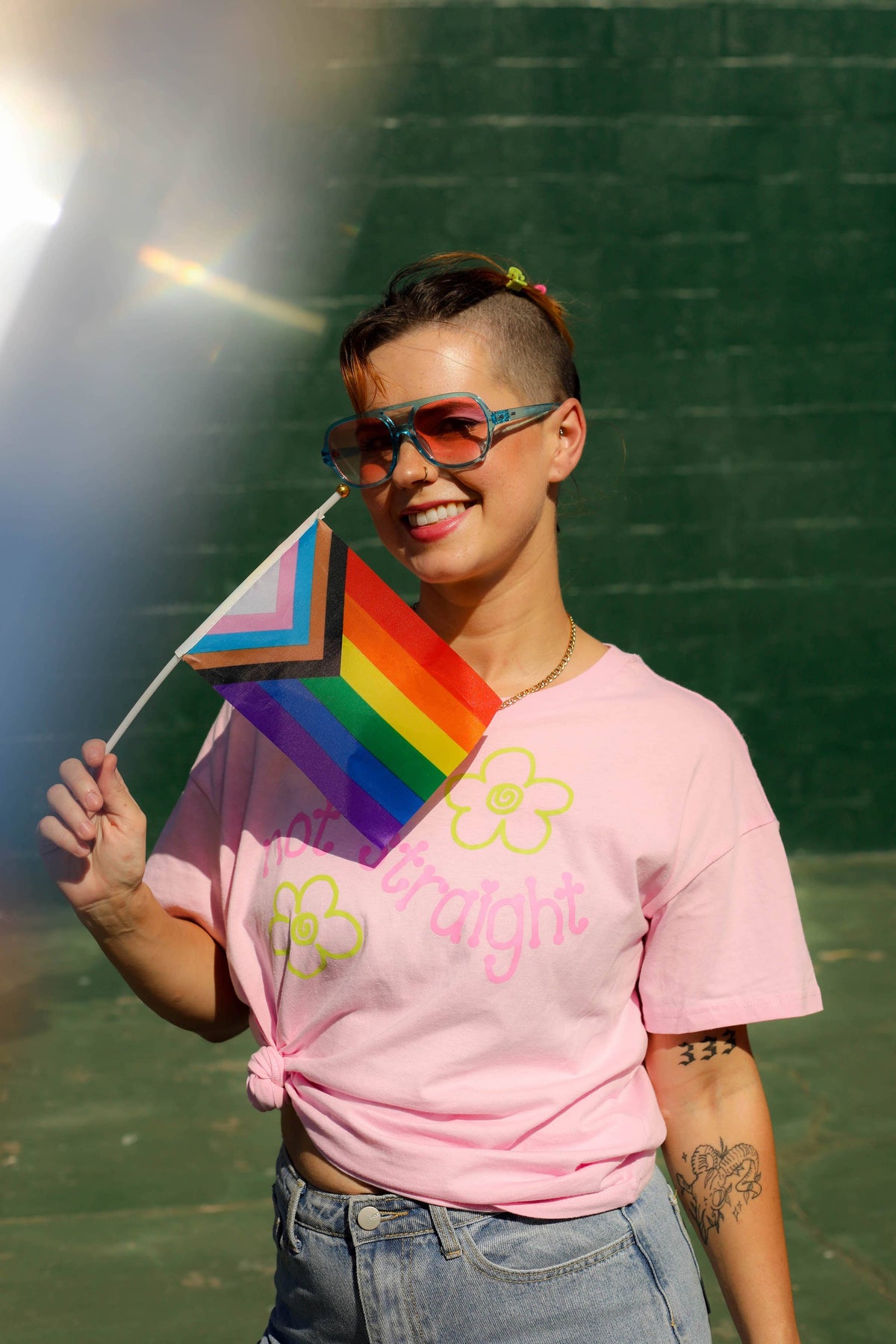 Person wearing a pink t-shirt with a rainbow flag