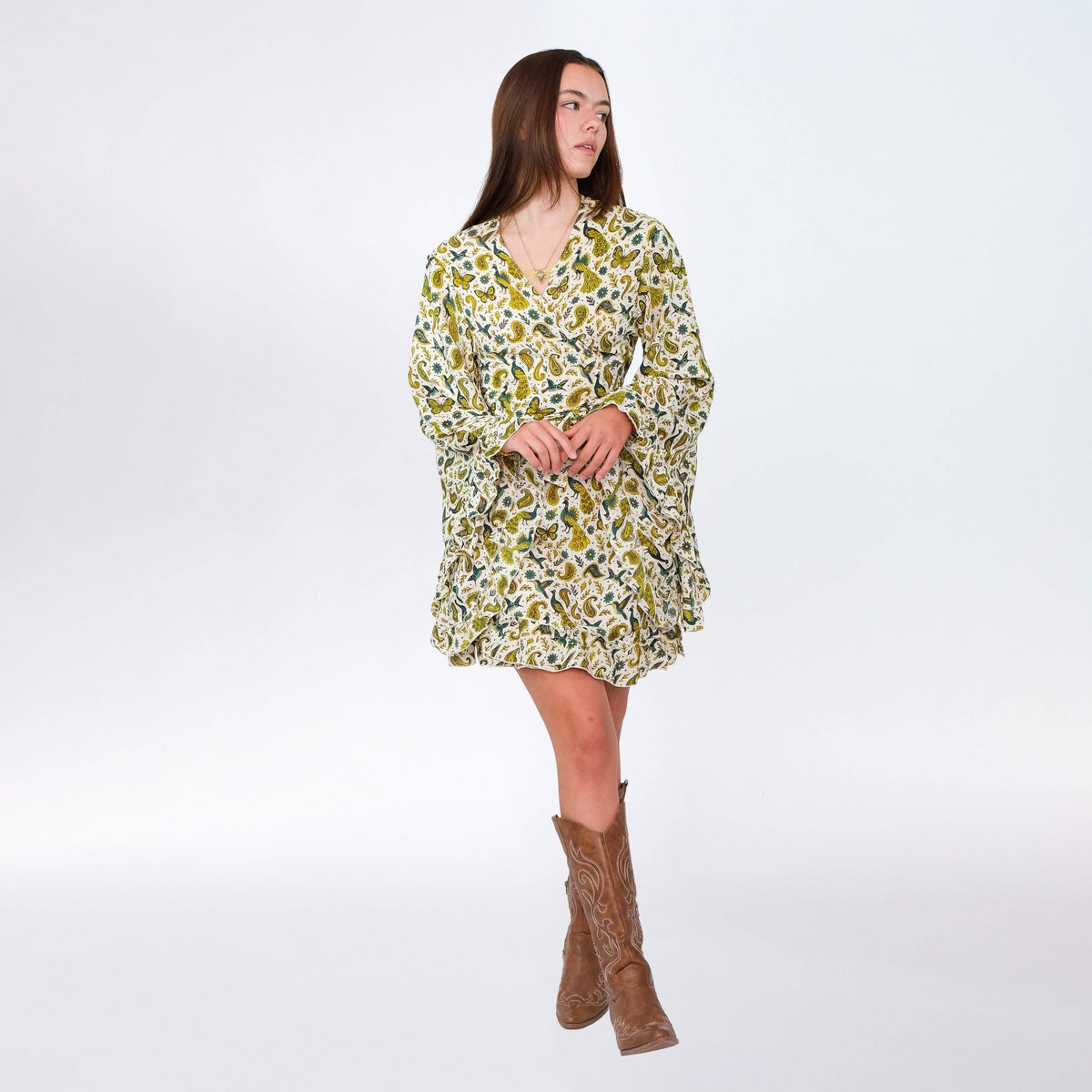 Woman wearing a floral dress and brown boots on a white background