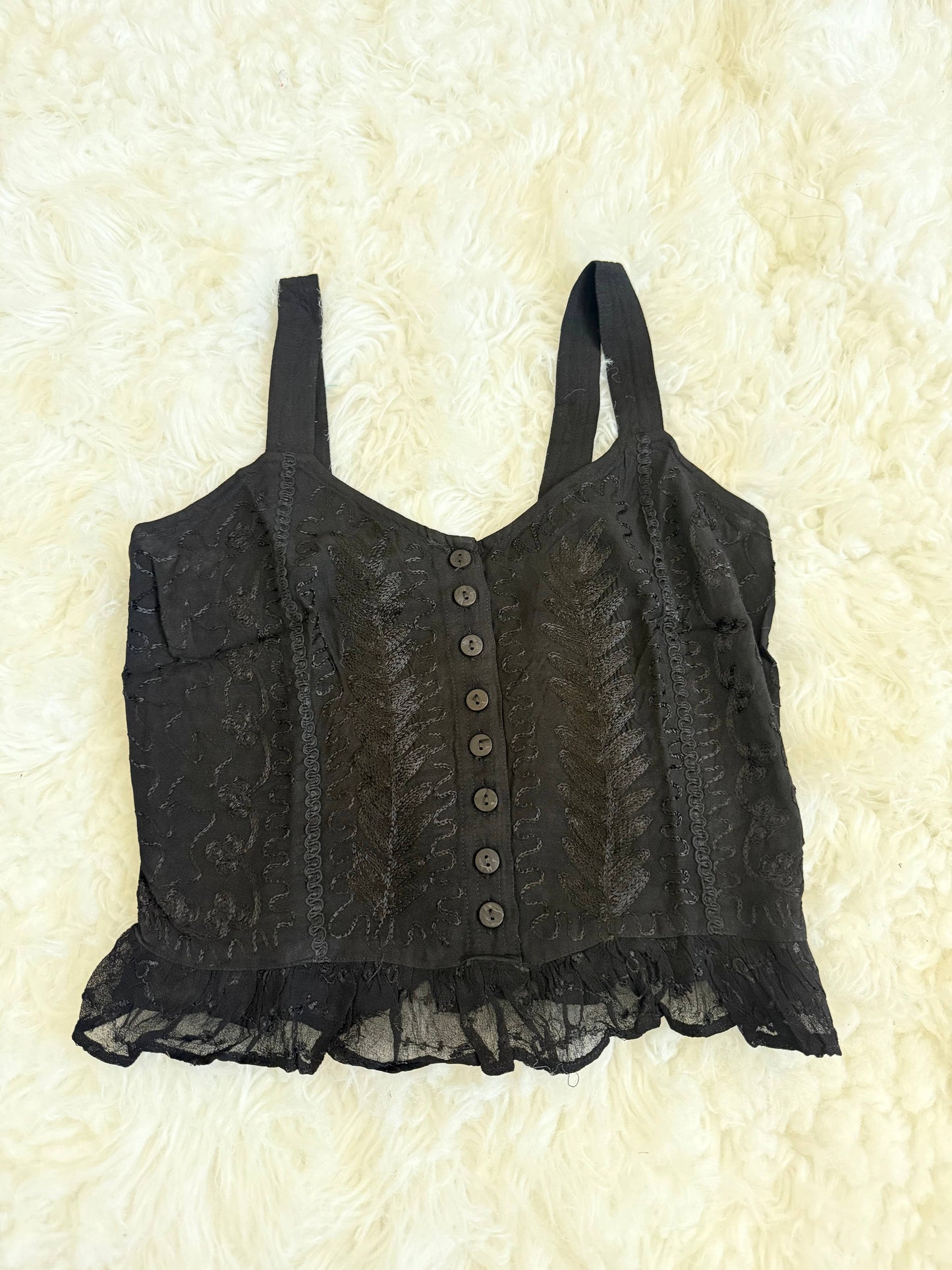 Black lace tank top on a textured beige background