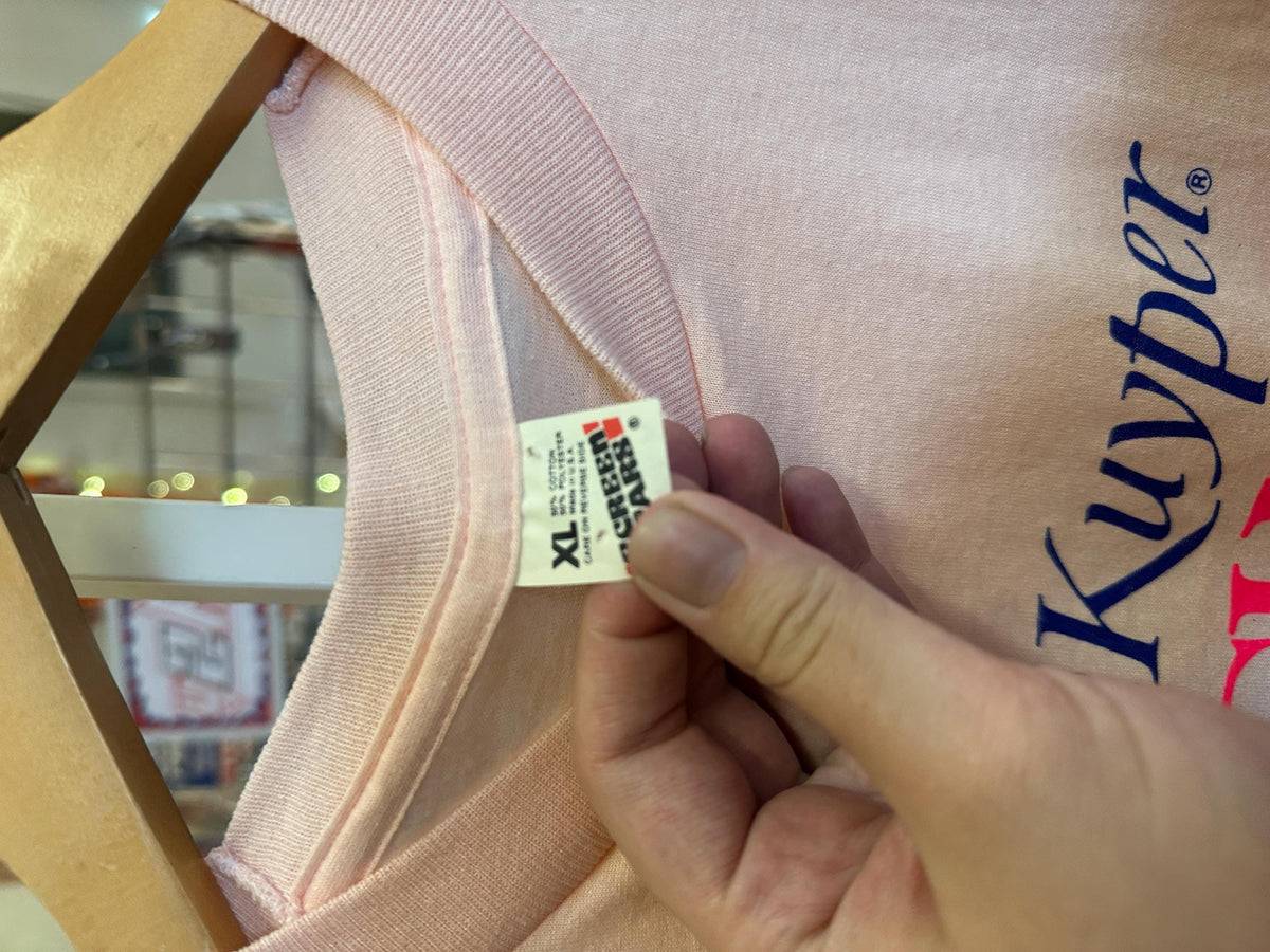 Close-up of a pink garment with a Kupon brand label, held by a hand.
