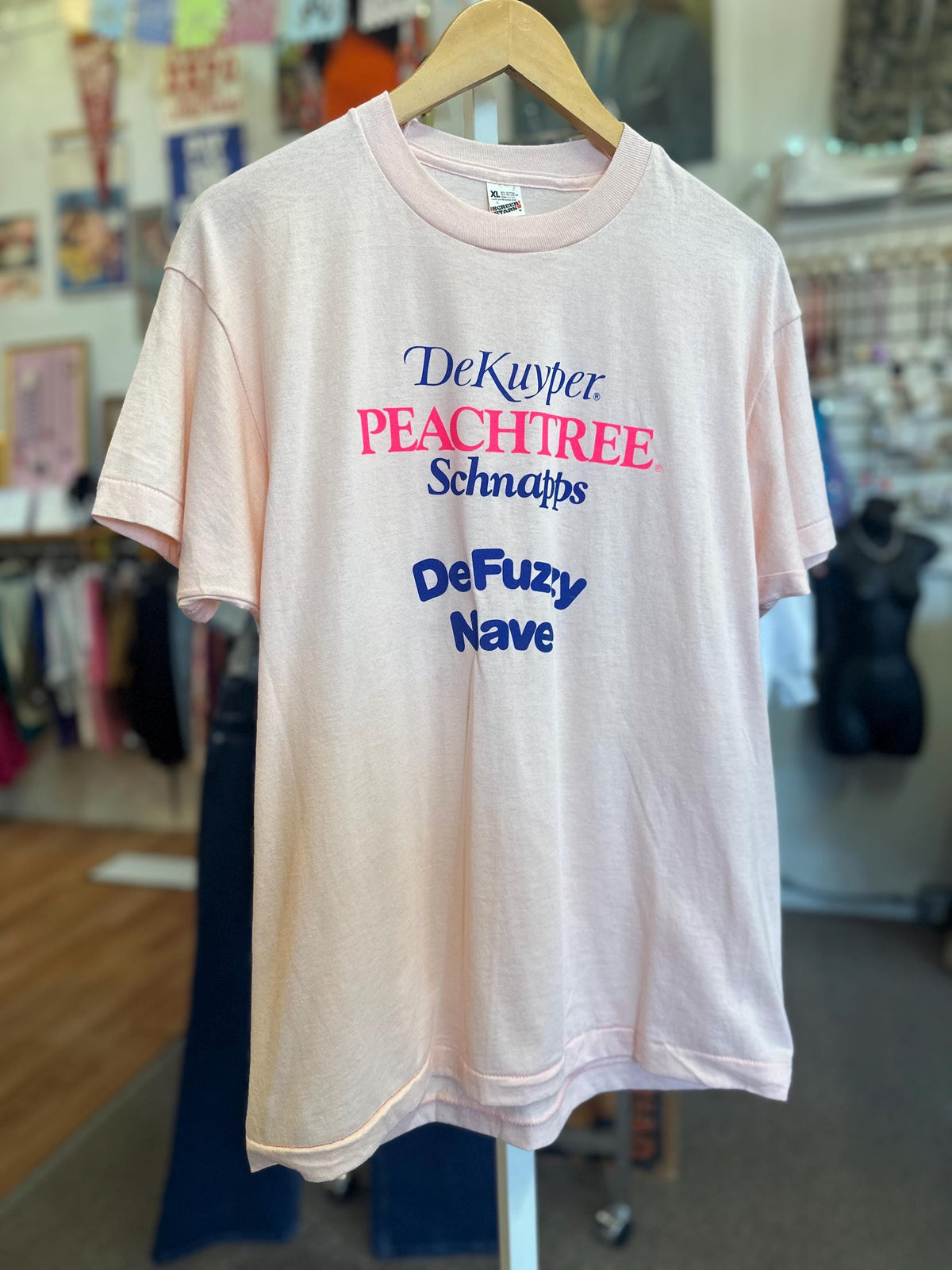 Pink t-shirt with colorful text on a hanger in a store setting