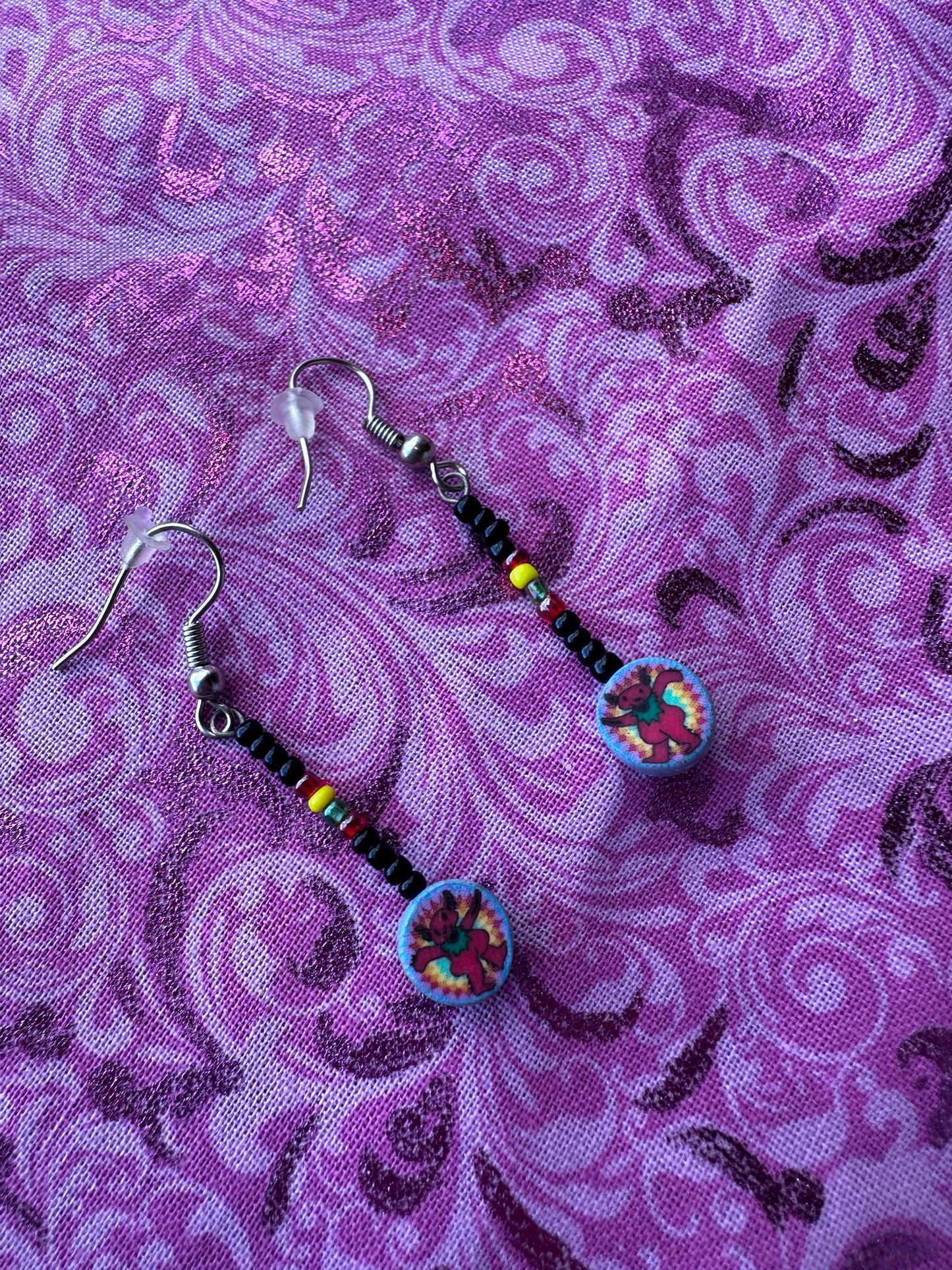 Pair of beaded earrings on a purple patterned fabric background