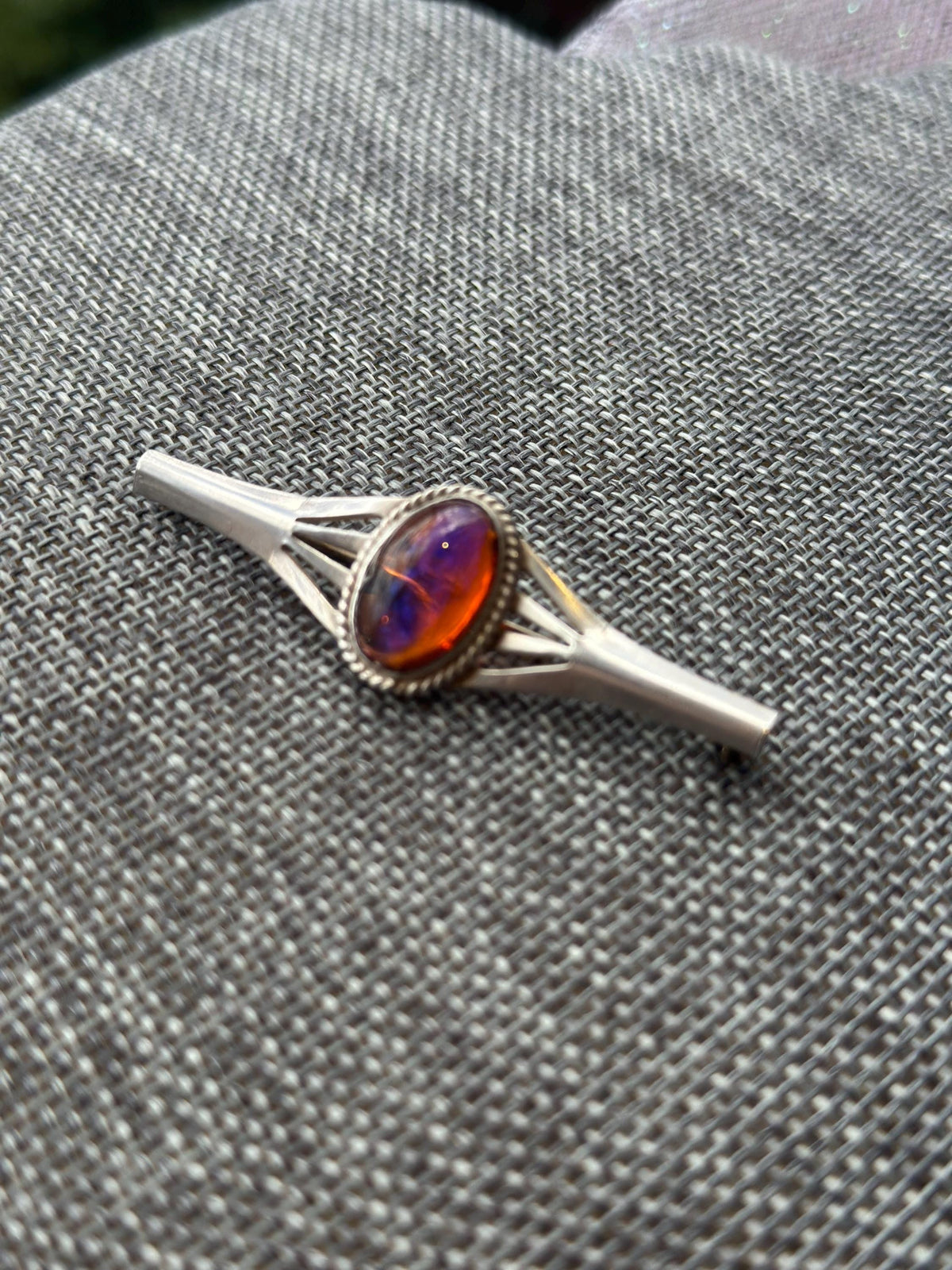 Silver ring with a colorful gemstone on a textured gray surface