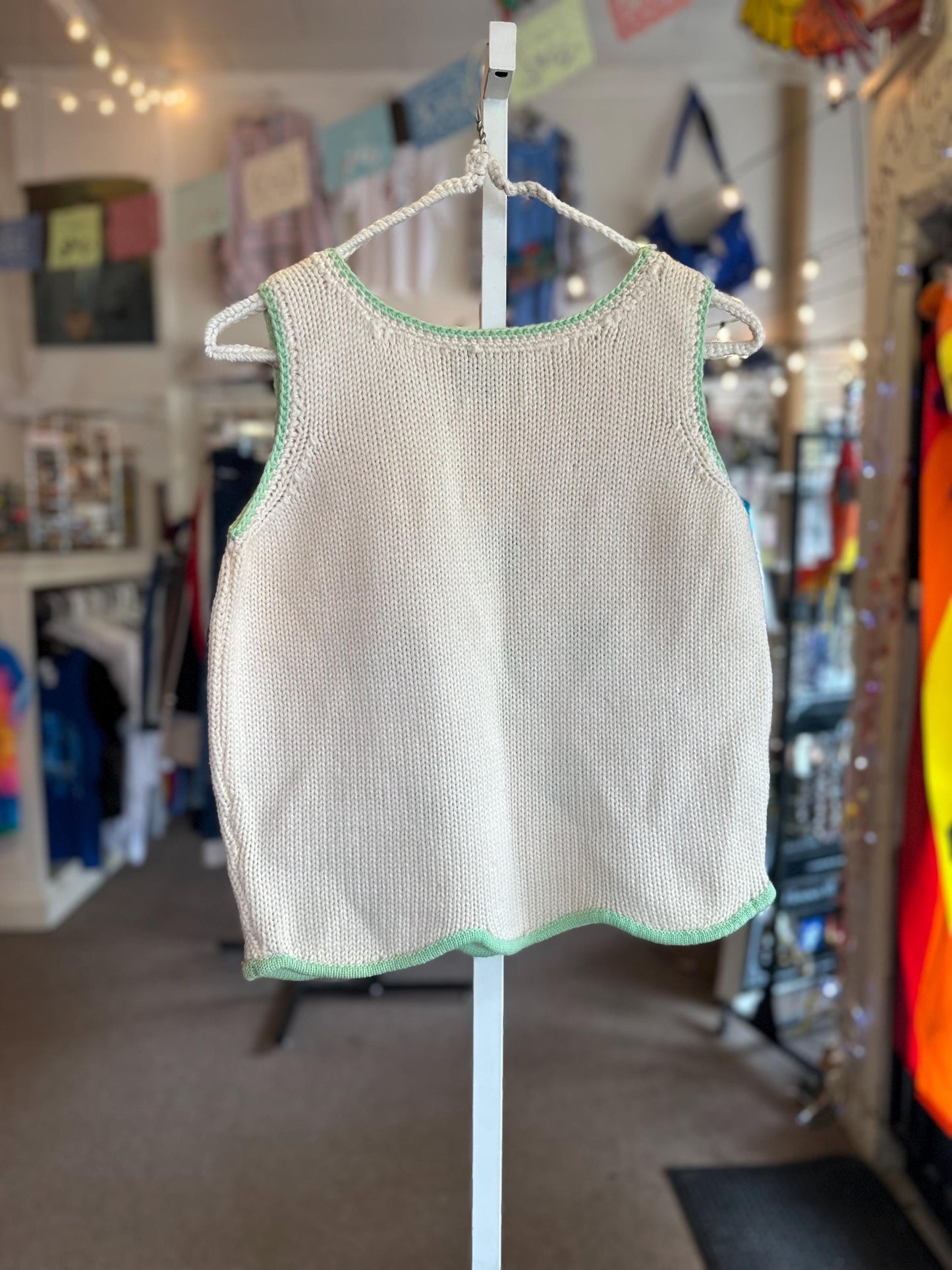Knitted tank top with green trim on a mannequin in a store setting