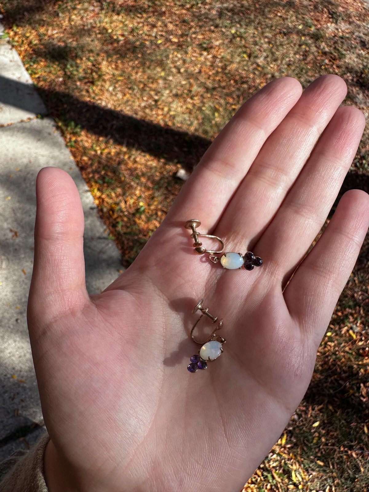 Hand wearing multiple rings with gemstones against a natural background
