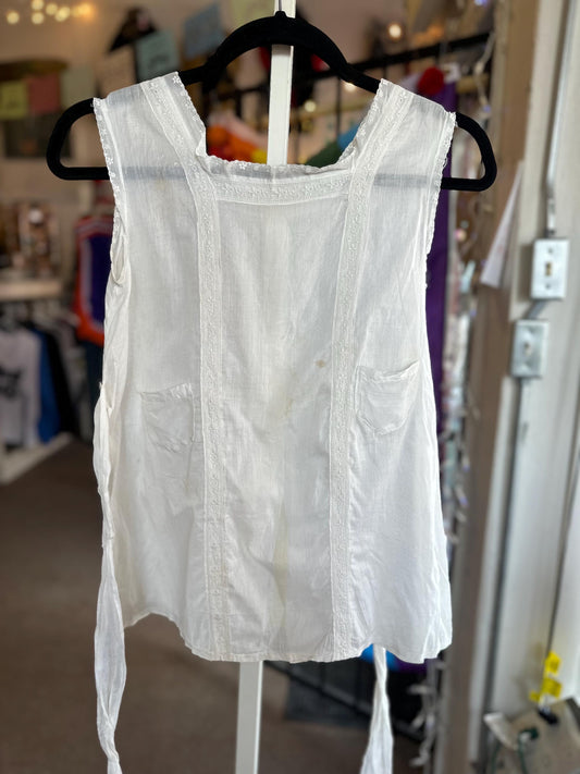 White sleeveless top hanging on a rack in a store setting