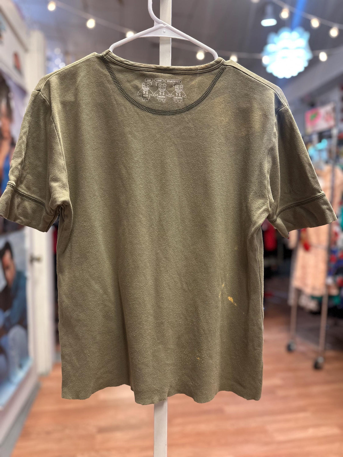 Green t-shirt on a hanger in a store setting