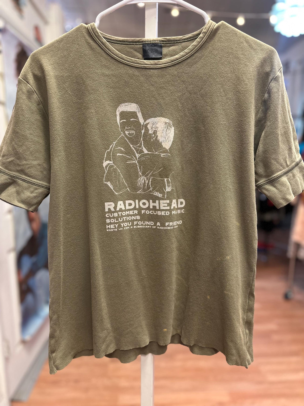 Green t-shirt with Radiohead graphic and text on a hanger