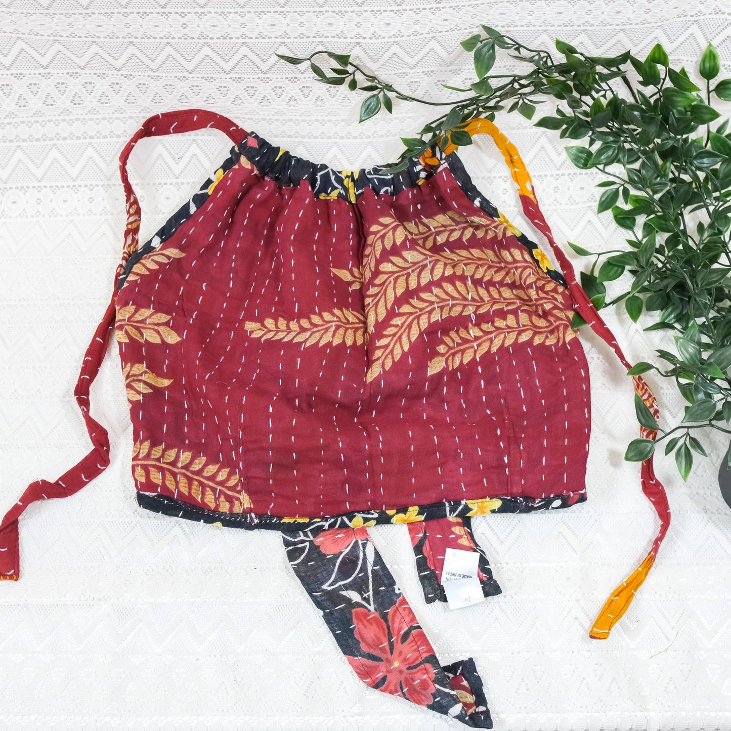 Red patterned apron with floral accents on a white background