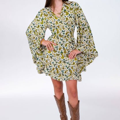 Woman wearing a patterned dress with long sleeves and brown cowboy boots on a white background