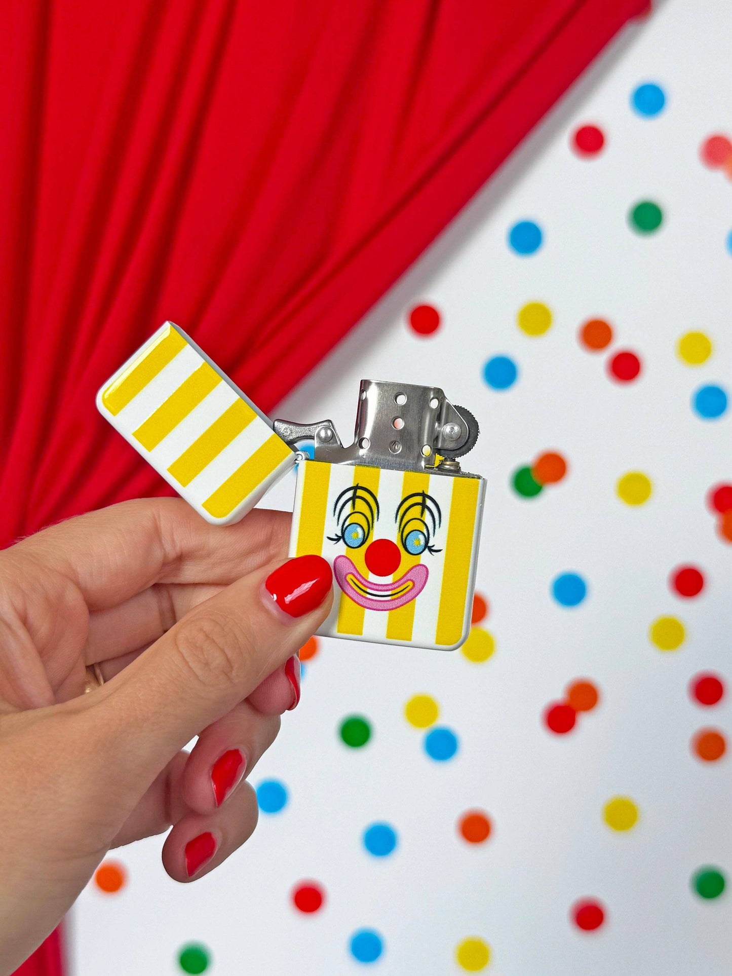 Hand holding a clown-themed lighter with a colorful polka dot background