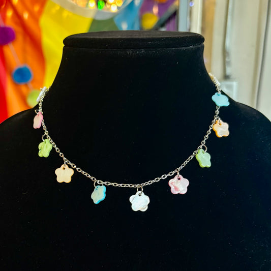Necklace with colorful flower-shaped pendants on a black mannequin against a colorful background