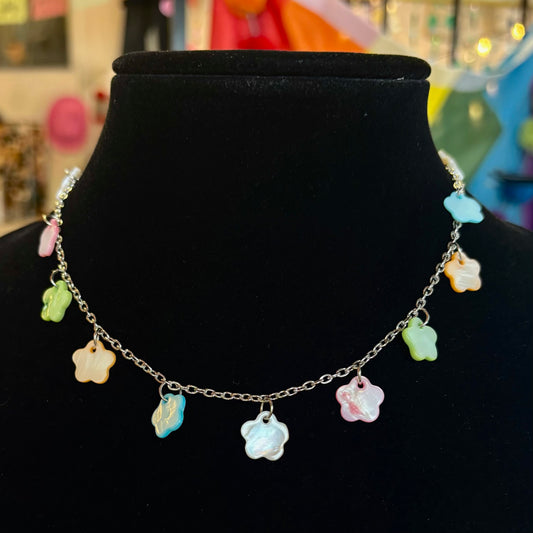 Necklace with colorful flower-shaped pendants on a black mannequin.