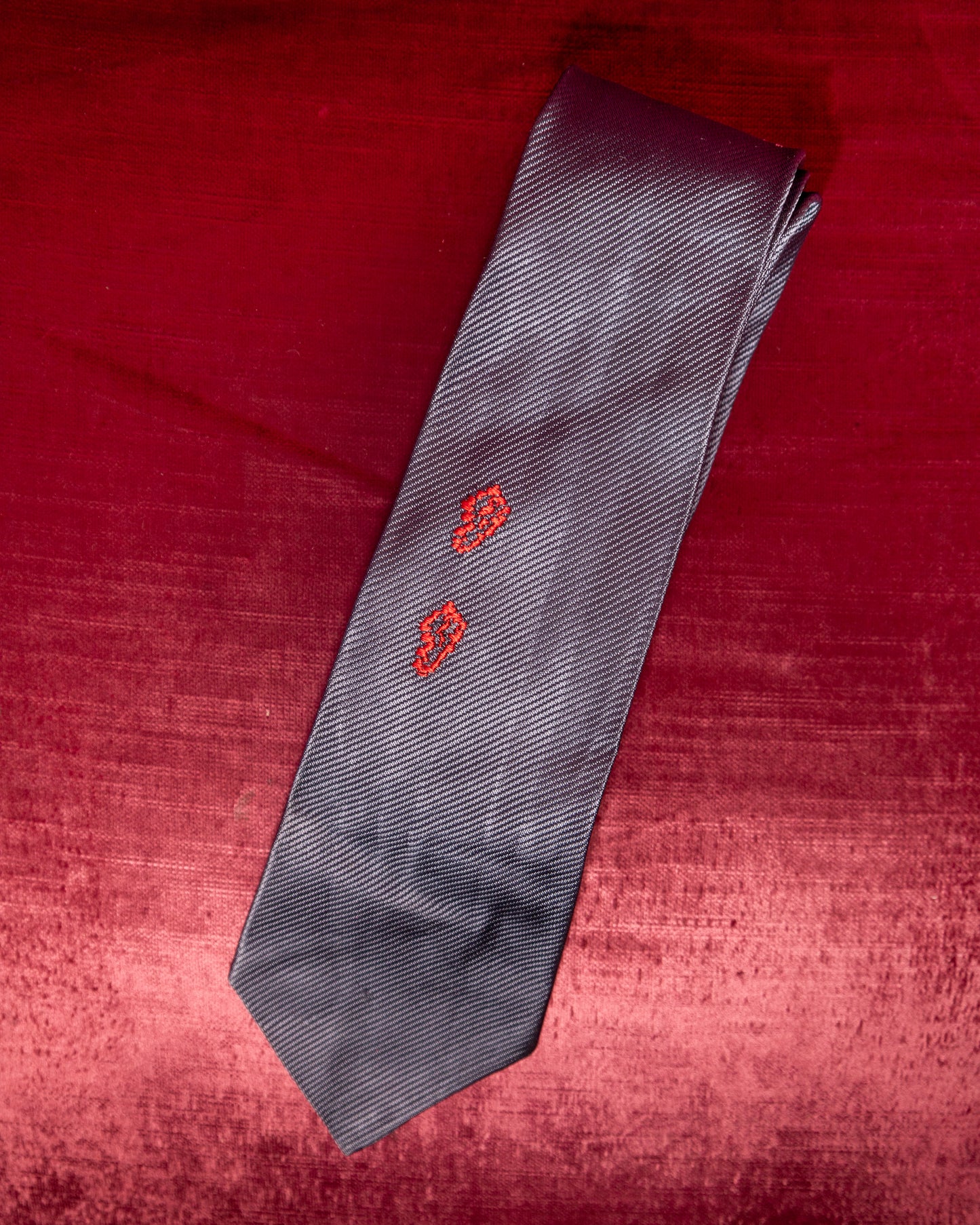 Gray tie with red patterns on a red textured background