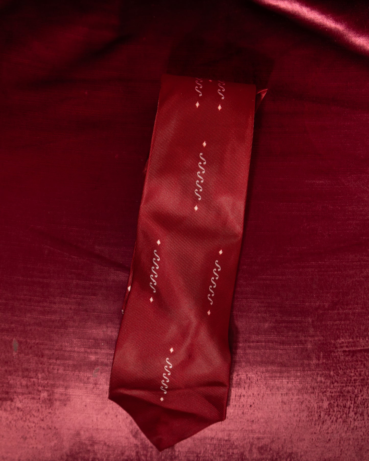 Red tie with decorative patterns on a red fabric background