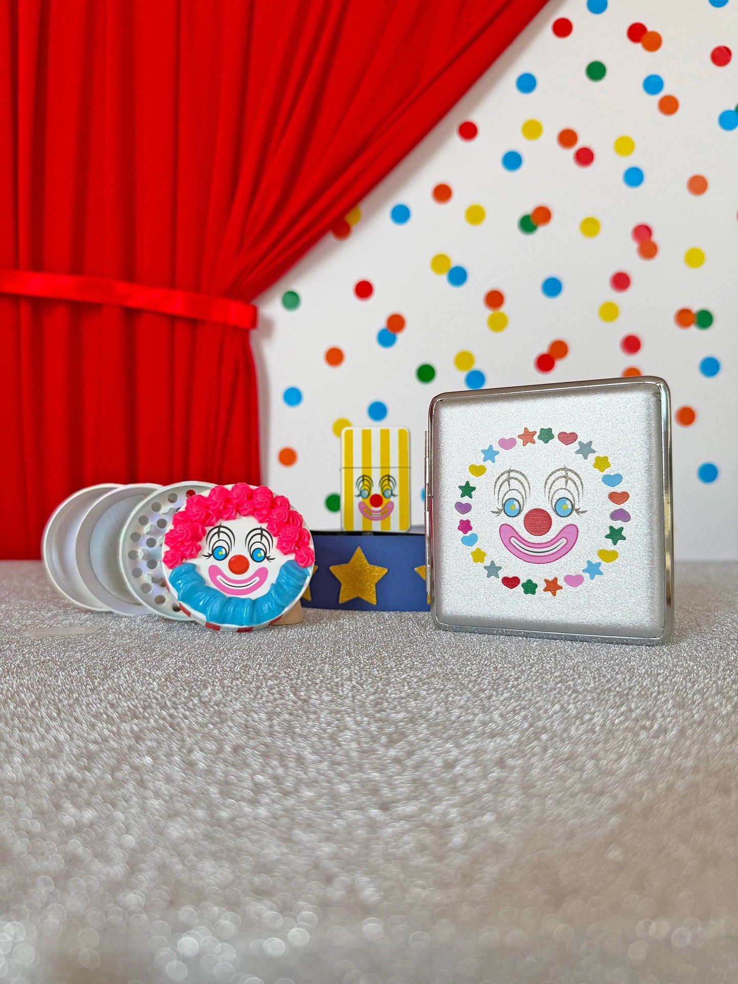 Decorative items with clown designs on a tablecloth with a red curtain and polka dot wall in the background.