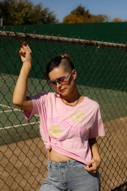 Person wearing a pink t-shirt with floral designs on a tennis court.