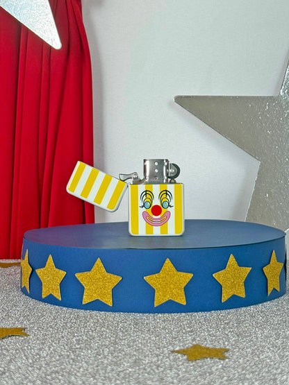 Lighter with clown face design on a blue stand with yellow stars, red curtain in the background