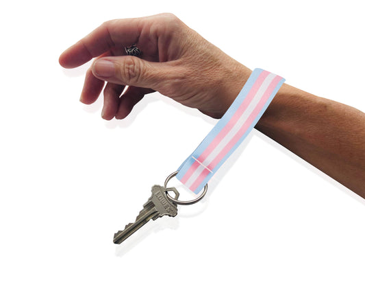 Hand holding a key with a striped keychain on a white background
