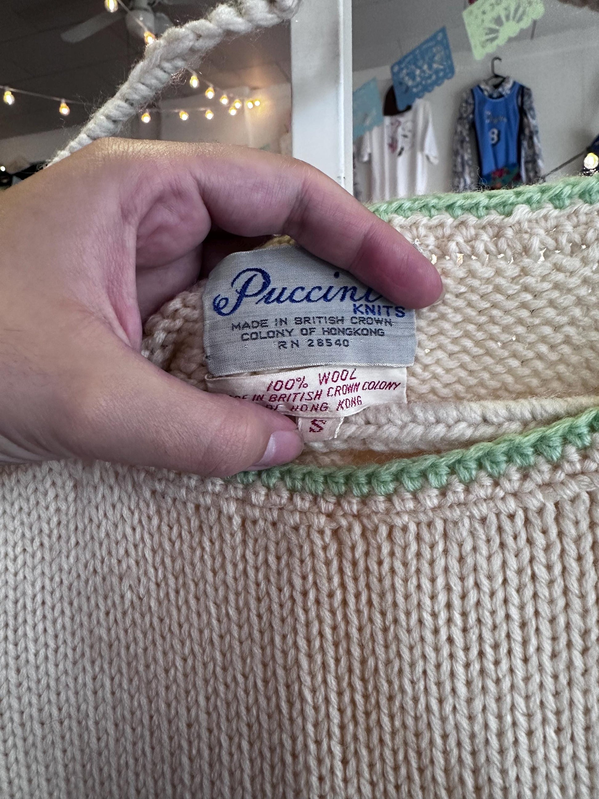 Hand holding a Puccini label on a knitted item with a blurred background