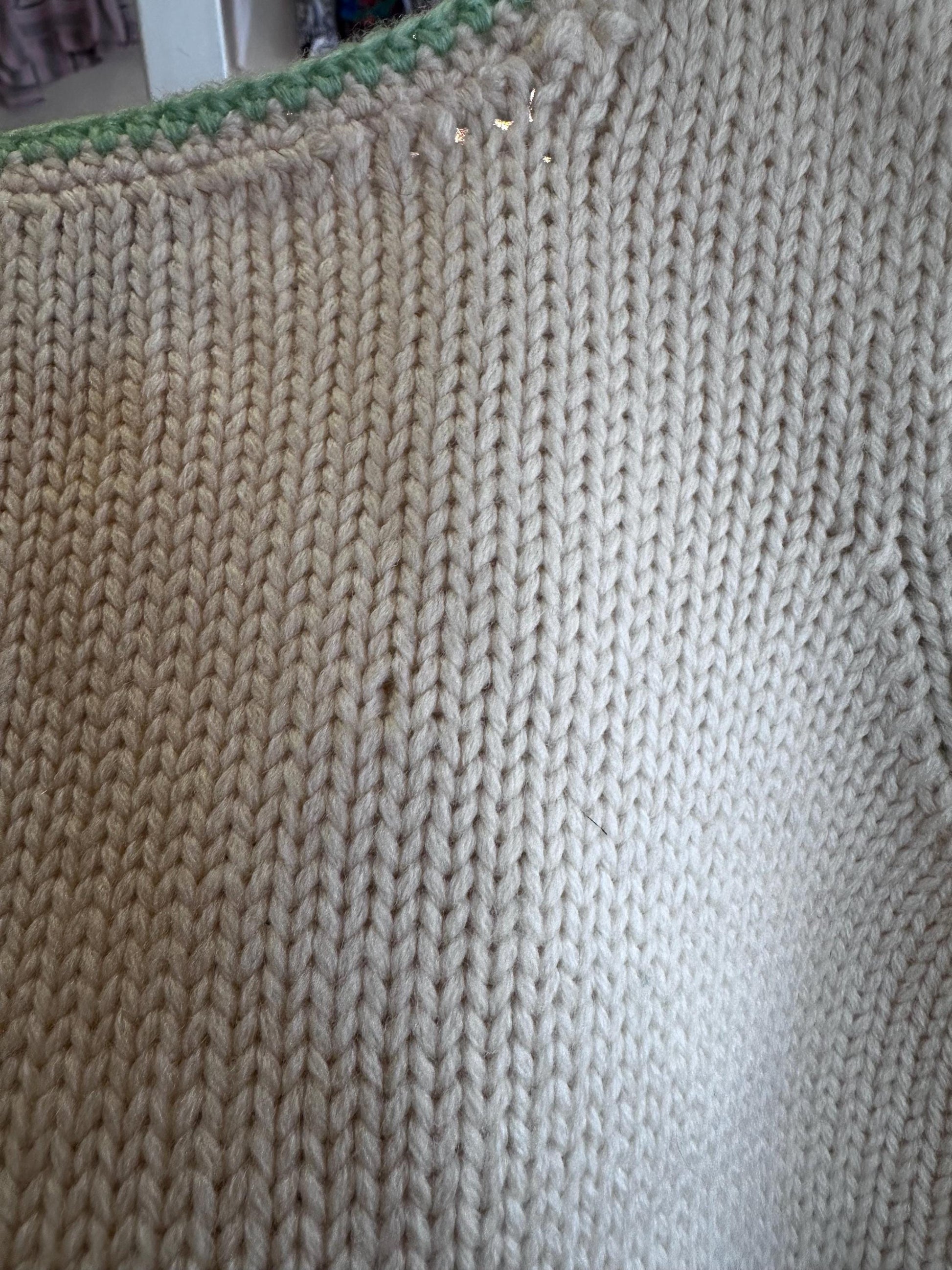 Close-up of a beige knitted fabric with a green border.
