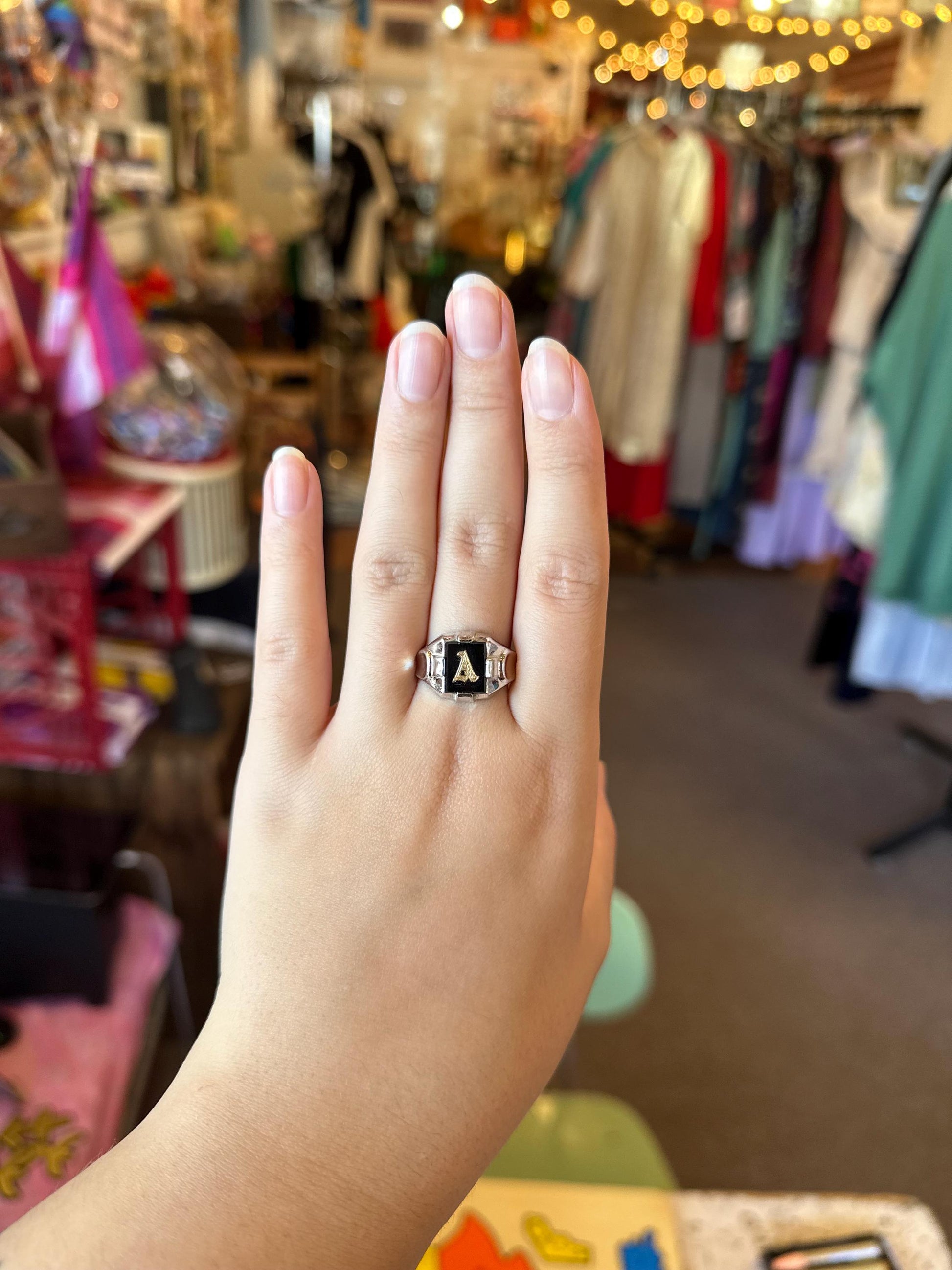 Hand wearing a ring with a store interior in the background
