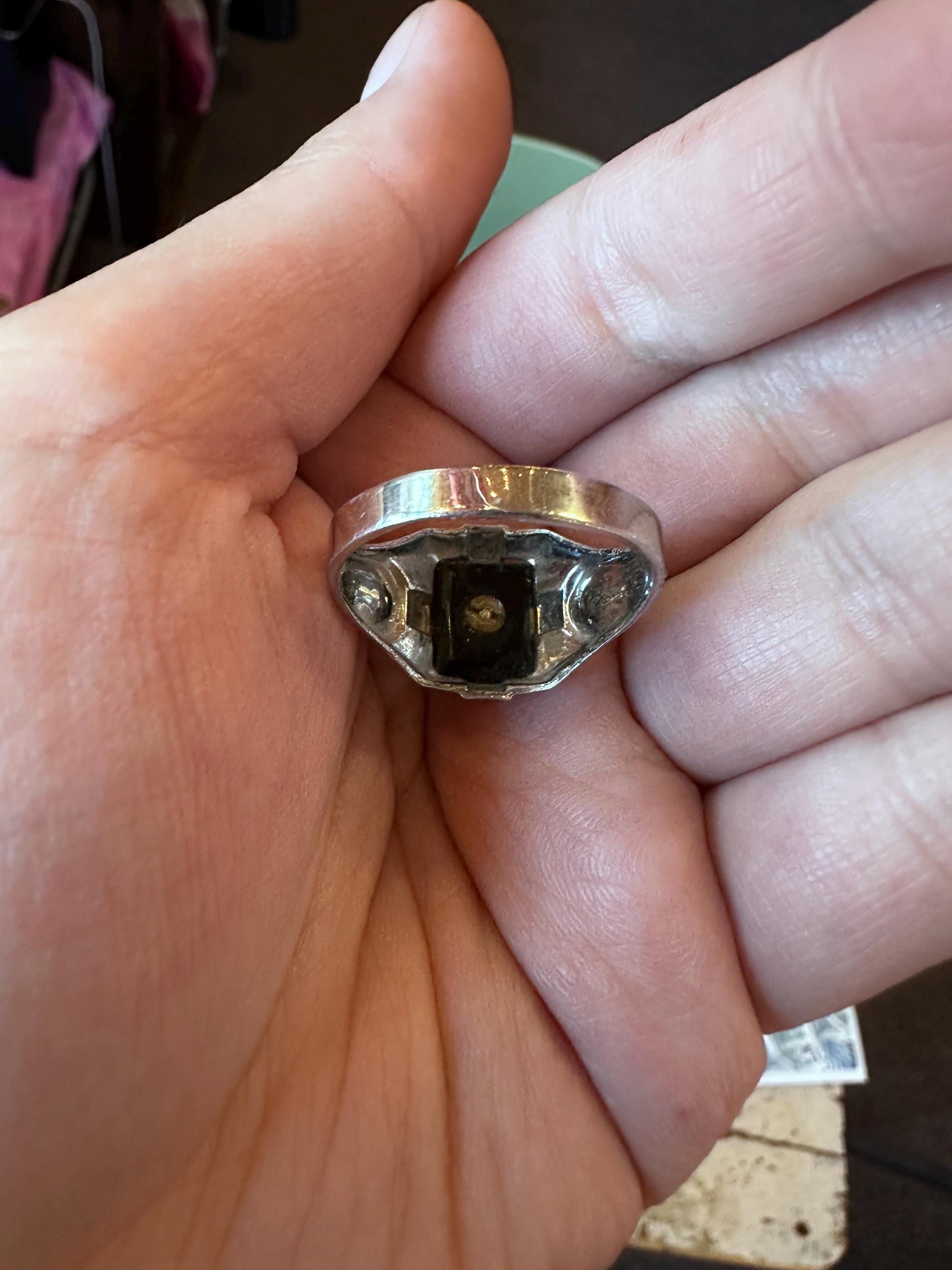 Silver ring held between fingers against a neutral background