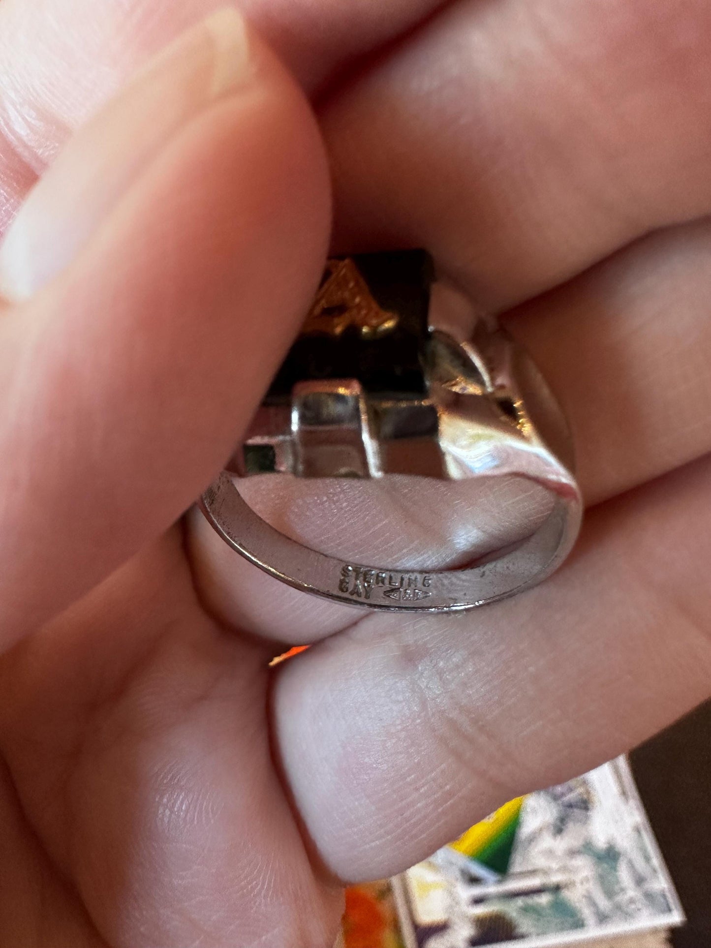 Close-up of a hand holding a silver ring with 'Exquisite' engraving.