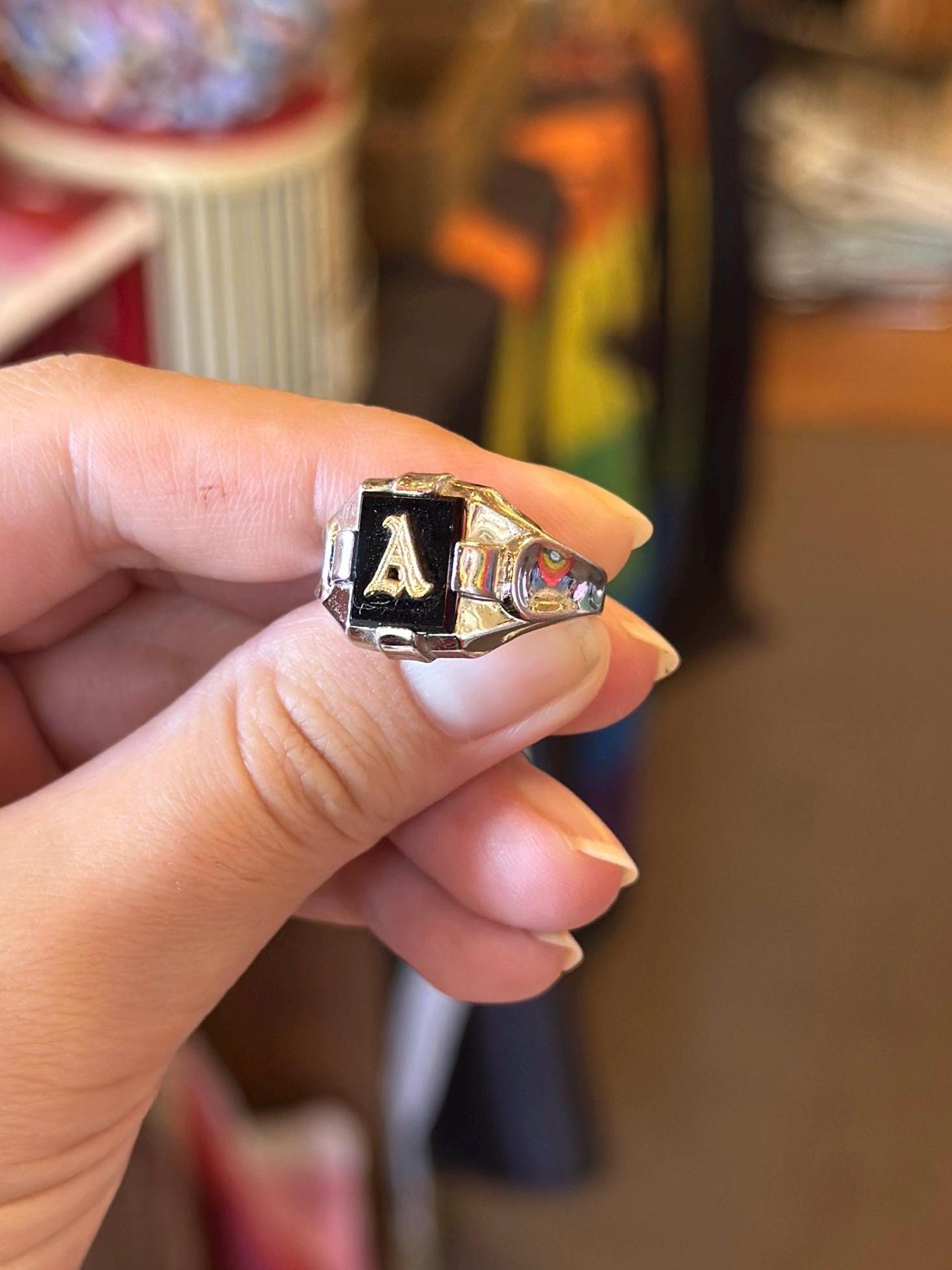 Hand holding a ring with a letter 'A' on a blurred background