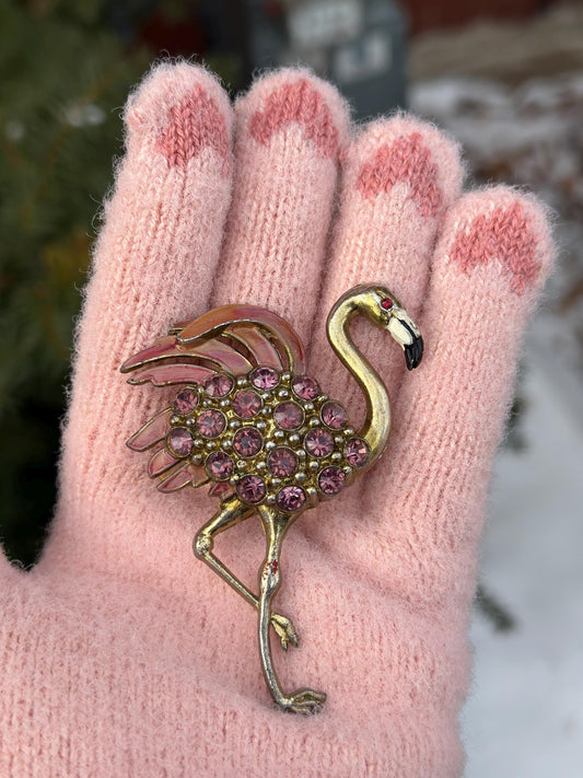 Flamingo brooch with pink stones on a pink glove against a blurred background