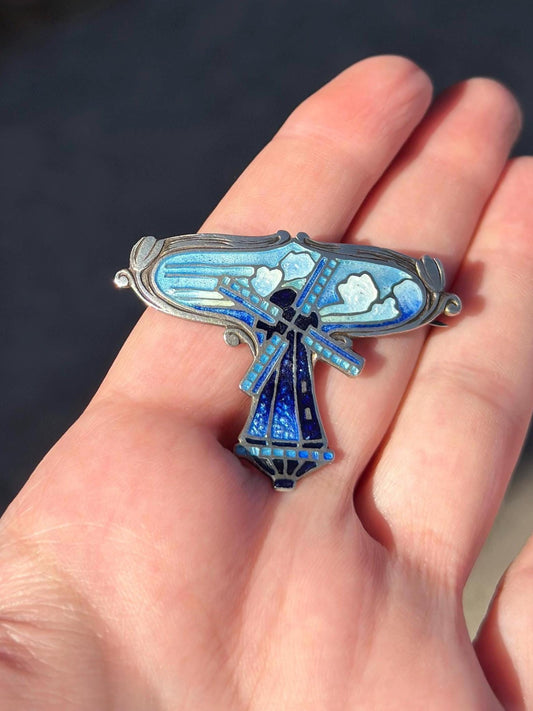 Blue and silver decorative object held in a hand against a dark background